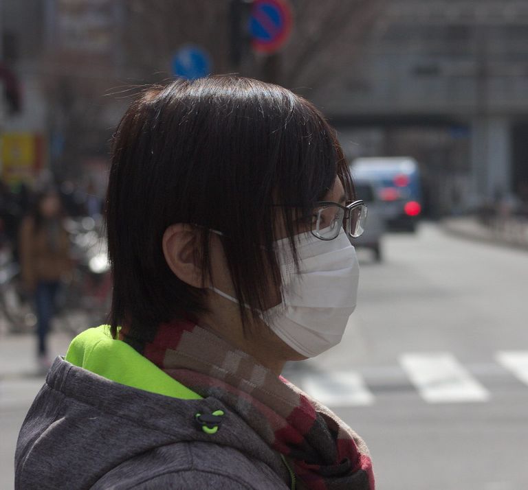 A person wearing a white face mask, representing measures that help prevent the spread of respiratory infections.