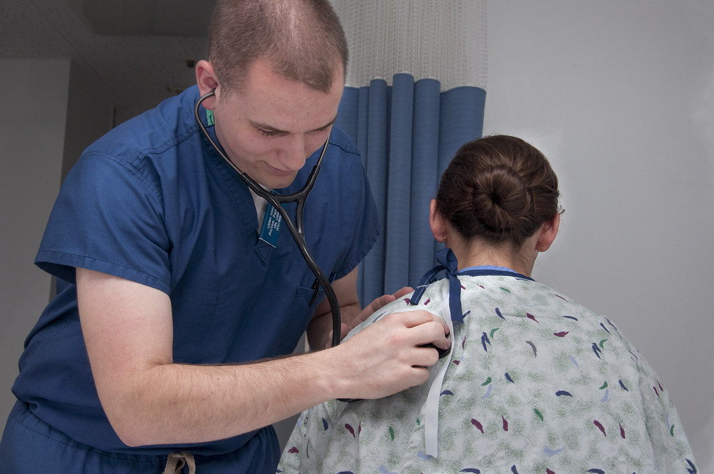 A nurse using a stethoscope to examine and monitor a patient