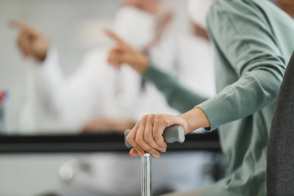 A senior using a walking cane with support from healthcare professionals